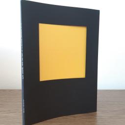 Das Foto zeigt das Buch zur Arbeit "Ich weiß, wie es ist". Das Buch hat einen schwarzen Umschlag. Der Titel steht in weiß auf dem Buchrücken. Vorne ist im Umschlag ein Ausschnitt. Dahinter ist eine gelbe Farbfläche zu sehen.