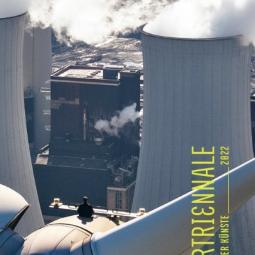 Ein Man sitzt auf einem Windradkraftwerk und sieht auf die Kühltürme eine Atomkraftwerks. Das bild hat Wasserzeichen mit Texte: Ruhrtriennale Festival der Künste 2022. 