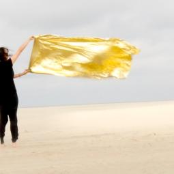 Eine schwarz gekleidete Frau mit einer gelben Flake auf Strand
