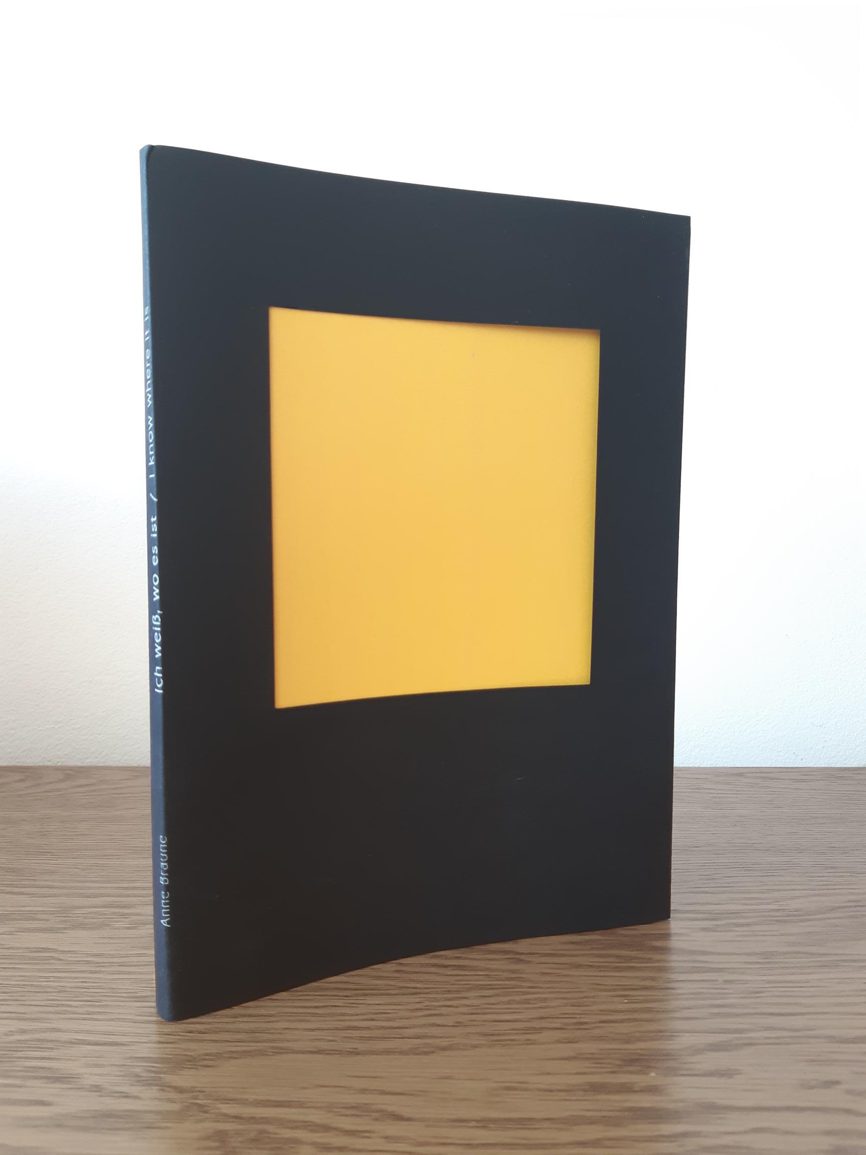 Das Foto zeigt das Buch zur Arbeit "Ich weiß, wie es ist". Das Buch hat einen schwarzen Umschlag. Der Titel steht in weiß auf dem Buchrücken. Vorne ist im Umschlag ein Ausschnitt. Dahinter ist eine gelbe Farbfläche zu sehen.